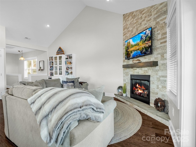 living room with a stone fireplace, dark hardwood / wood-style floors, and high vaulted ceiling