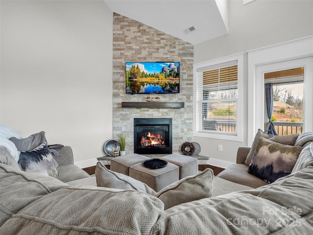 living room featuring hardwood / wood-style flooring, a stone fireplace, and high vaulted ceiling