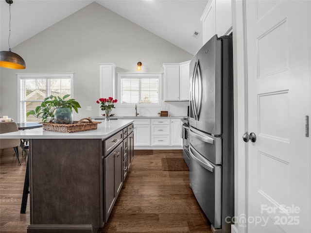 kitchen with dark hardwood / wood-style floors, stainless steel appliances, decorative light fixtures, and white cabinets