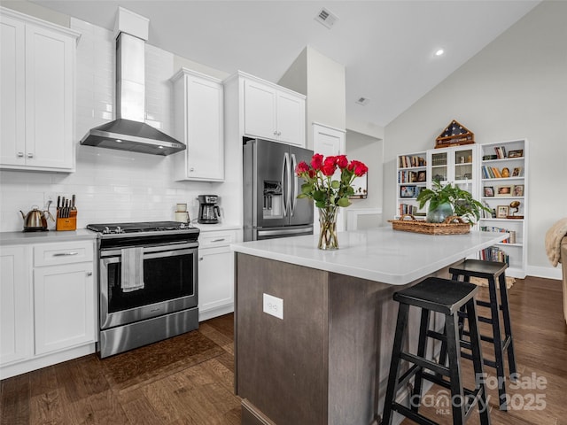 kitchen featuring wall chimney exhaust hood, stainless steel appliances, and white cabinets