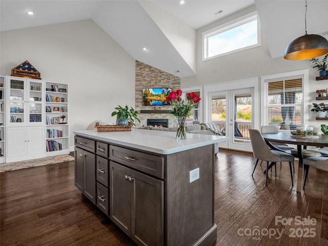 kitchen featuring dark brown cabinetry, decorative light fixtures, dark hardwood / wood-style flooring, and a kitchen island