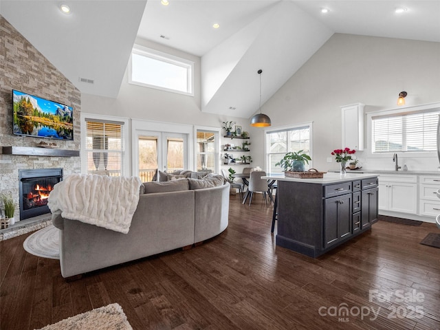 living room featuring dark hardwood / wood-style flooring, sink, a fireplace, and high vaulted ceiling