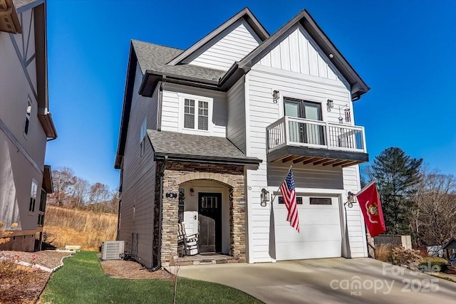 view of front of house featuring roof with shingles, a balcony, driveway, stone siding, and a garage