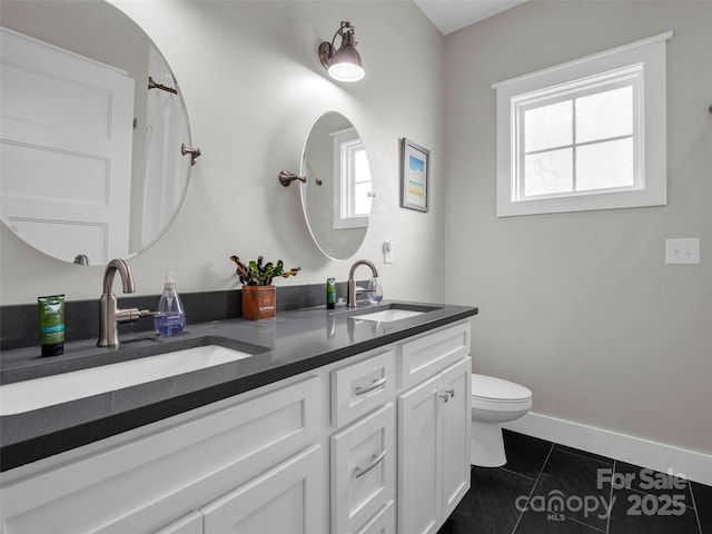 bathroom with tile patterned floors, vanity, toilet, and a wealth of natural light