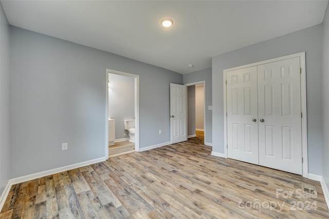 unfurnished bedroom with light wood-type flooring, a closet, and ensuite bathroom