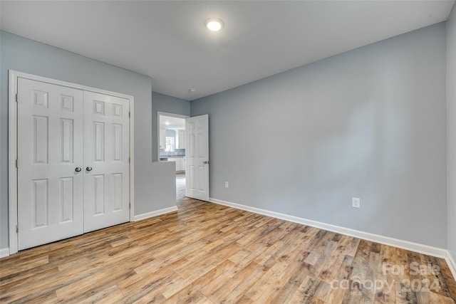 unfurnished bedroom with light hardwood / wood-style flooring and a closet