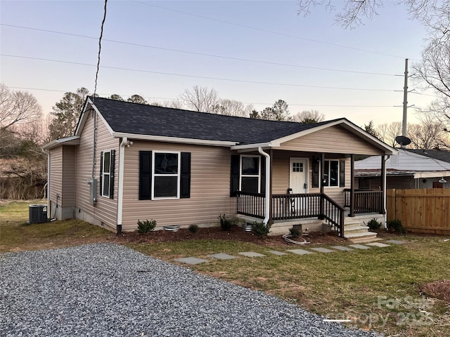 single story home featuring central air condition unit, covered porch, driveway, roof with shingles, and a front lawn