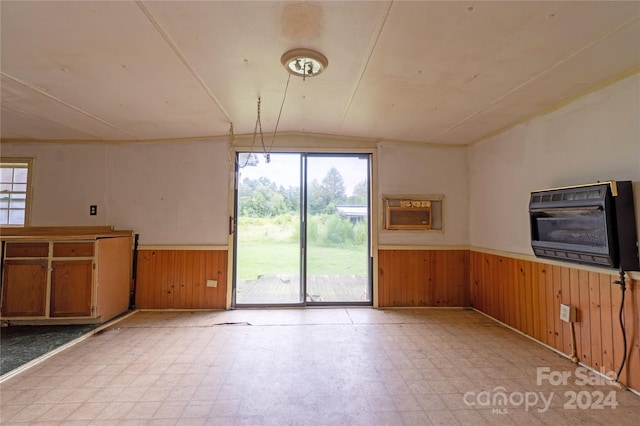 spare room featuring heating unit, wooden walls, and vaulted ceiling