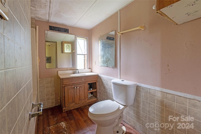 bathroom featuring vanity, hardwood / wood-style flooring, tile walls, and toilet