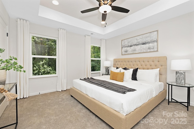 carpeted bedroom featuring ceiling fan and a tray ceiling