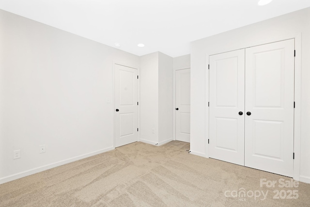 unfurnished bedroom with light colored carpet and a closet