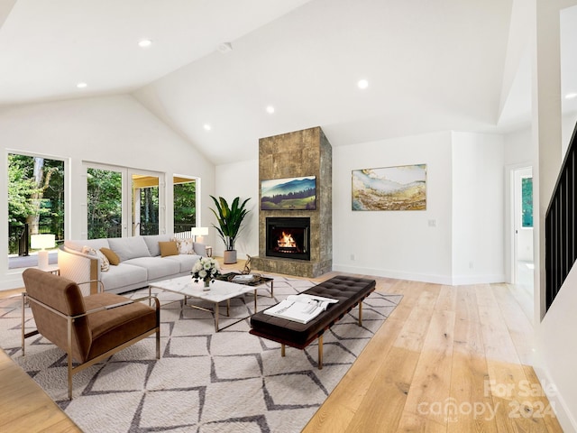 living room featuring a fireplace, high vaulted ceiling, and light hardwood / wood-style flooring