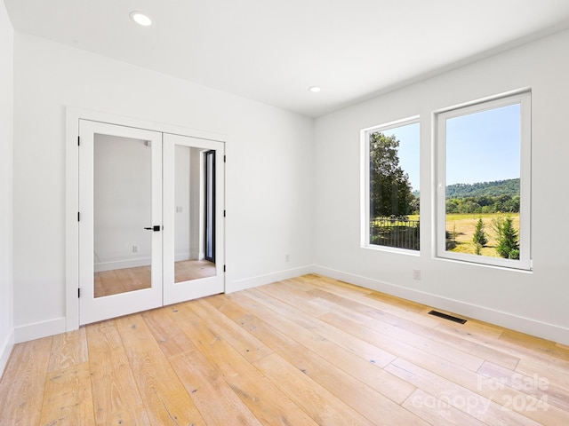 unfurnished bedroom with french doors and light hardwood / wood-style flooring