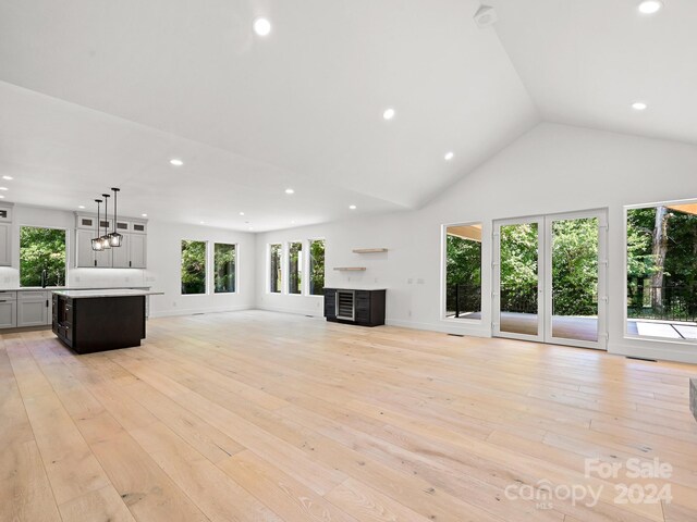 unfurnished living room featuring a fireplace, high vaulted ceiling, sink, and light hardwood / wood-style floors