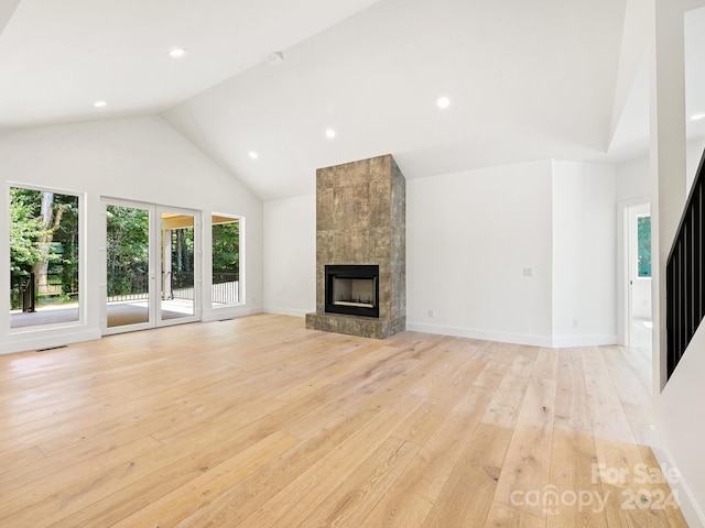 unfurnished living room featuring light hardwood / wood-style flooring, high vaulted ceiling, and a fireplace