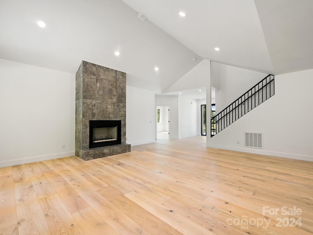 unfurnished living room with a large fireplace, high vaulted ceiling, and light hardwood / wood-style floors