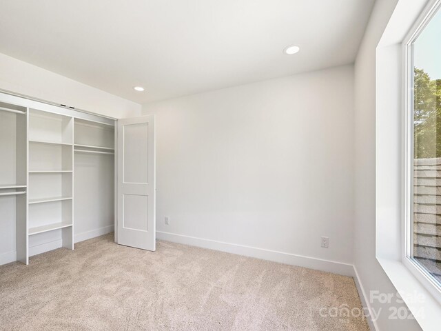 unfurnished bedroom featuring a closet and light colored carpet