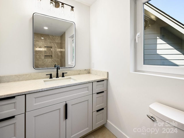 bathroom with tile patterned floors, toilet, a tile shower, and vanity