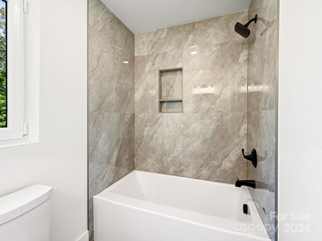 bathroom with toilet and tiled shower / bath combo