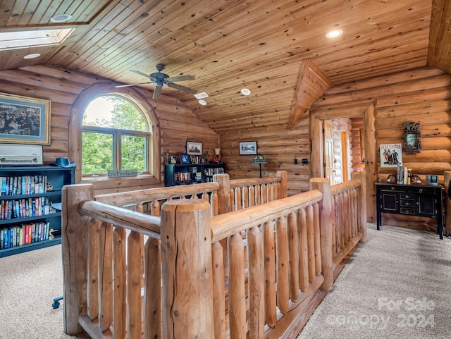 interior space featuring wooden ceiling, vaulted ceiling with skylight, ceiling fan, and rustic walls