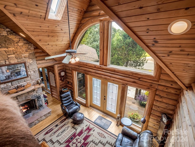 living room featuring ceiling fan, a skylight, wood ceiling, hardwood / wood-style flooring, and a fireplace