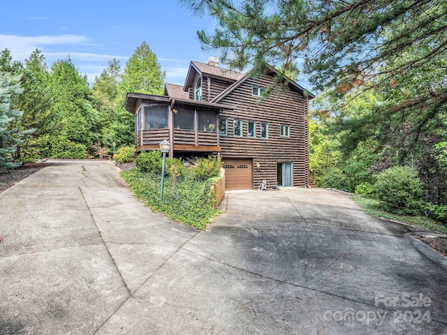 181 Highland Hts, Lake Lure, NC 28746 - view of side of property with a sunroom, driveway, a chimney, log siding, and an attached garage