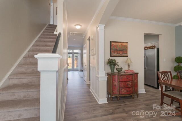 entrance foyer with crown molding, decorative columns, and dark hardwood / wood-style floors