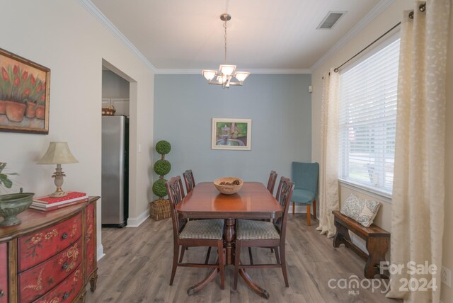 dining room featuring light wood-type flooring, crown molding, and a healthy amount of sunlight