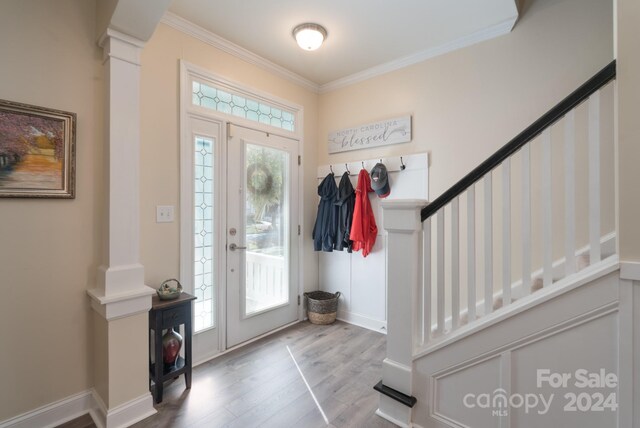 entrance foyer featuring decorative columns, hardwood / wood-style floors, crown molding, and a wealth of natural light