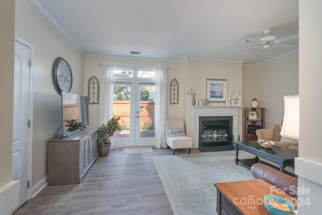 living room with wood-type flooring, french doors, ornamental molding, and ceiling fan