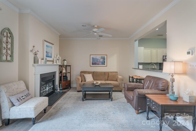 living room with crown molding, sink, ceiling fan, and light colored carpet