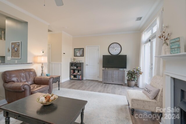 living room with ornamental molding, light hardwood / wood-style floors, and ceiling fan