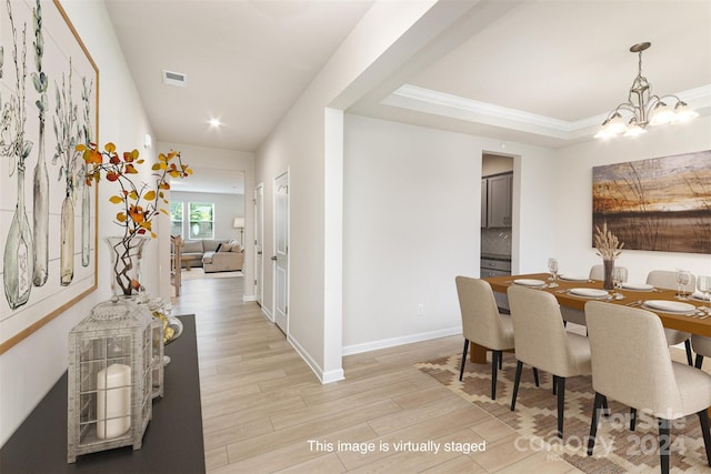 dining space featuring light hardwood / wood-style floors, ornamental molding, and a chandelier