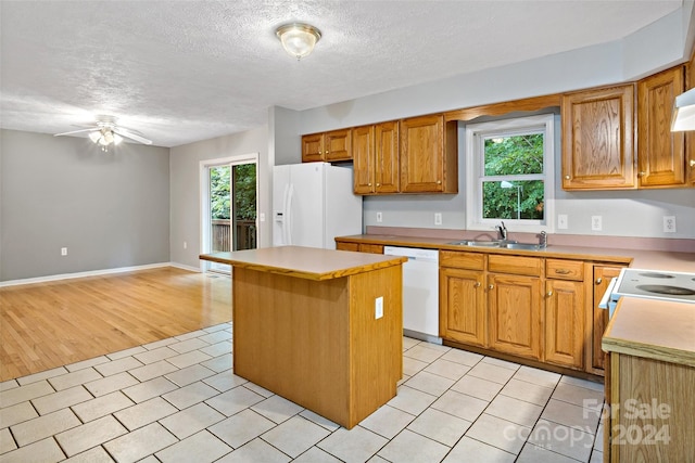 kitchen featuring a wealth of natural light, white appliances, light hardwood / wood-style floors, and a kitchen island