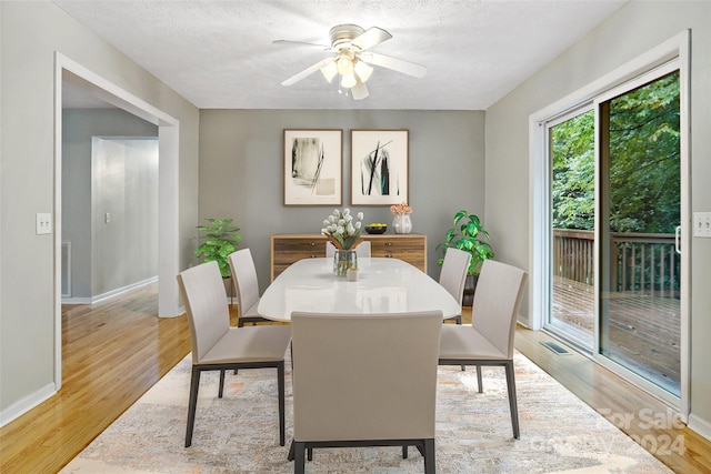 dining room featuring light hardwood / wood-style floors, ceiling fan, and a textured ceiling