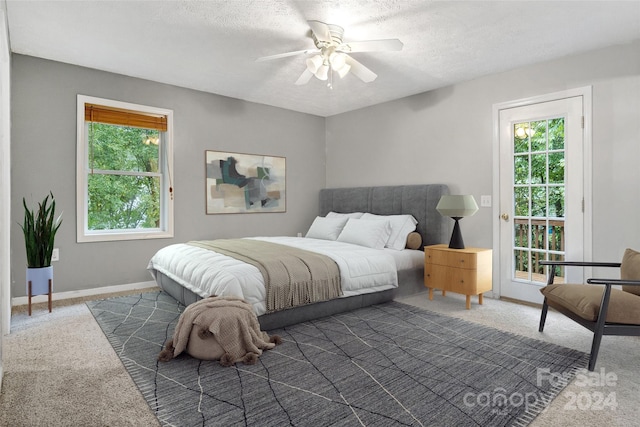 bedroom featuring a textured ceiling, dark carpet, ceiling fan, and access to exterior