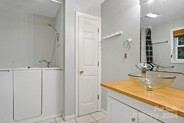 bathroom featuring vanity, shower / bath combo, a textured ceiling, and tile patterned floors