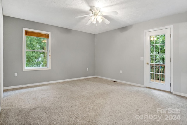 carpeted spare room with ceiling fan and a textured ceiling