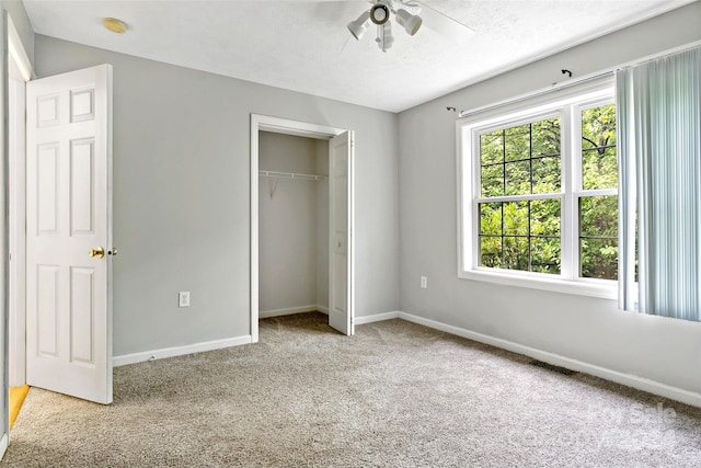 unfurnished bedroom with a textured ceiling, light carpet, ceiling fan, and a closet