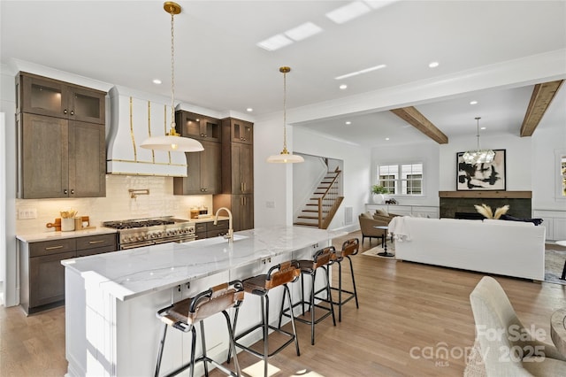 kitchen with a large island with sink, a kitchen breakfast bar, and range with two ovens