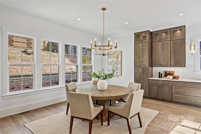 dining area with a notable chandelier and light hardwood / wood-style floors