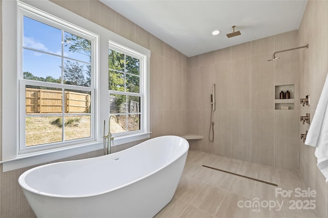 bathroom with a wealth of natural light, tile walls, tile patterned flooring, and shower with separate bathtub