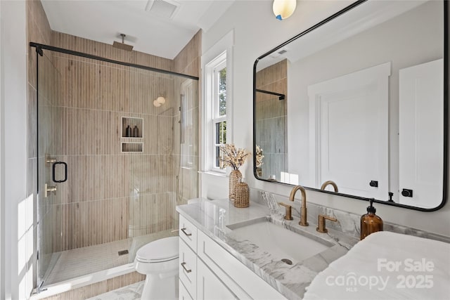 bathroom featuring toilet, vanity, and a shower with door