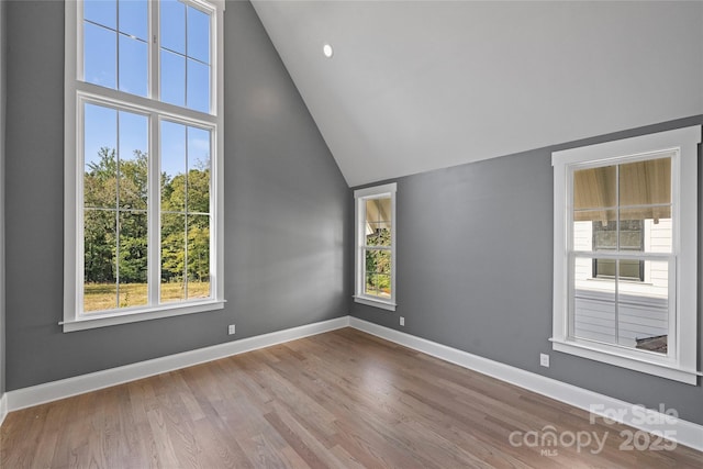 empty room with high vaulted ceiling and wood-type flooring