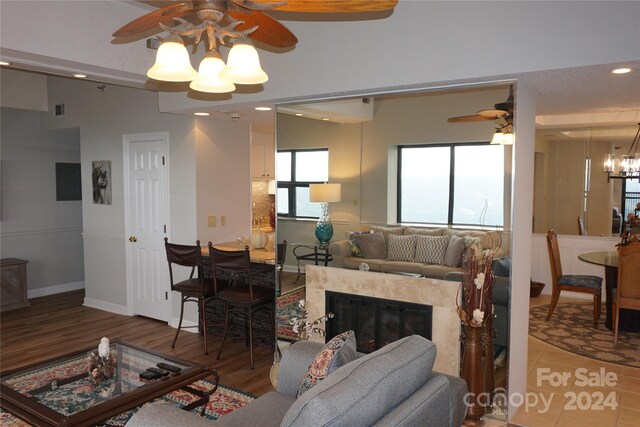 living room featuring ceiling fan with notable chandelier, a fireplace, and hardwood / wood-style flooring