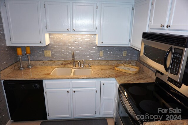 kitchen with black dishwasher, sink, white cabinets, decorative backsplash, and light stone countertops