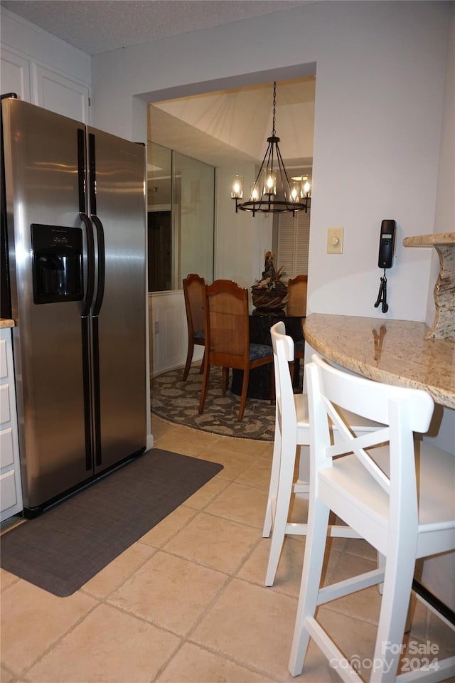 kitchen featuring light tile patterned flooring, decorative light fixtures, stainless steel fridge, and a chandelier