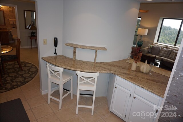 kitchen with light stone counters, white cabinets, and light tile patterned flooring