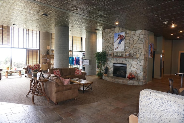 carpeted living room featuring ornate columns, a fireplace, and a wealth of natural light