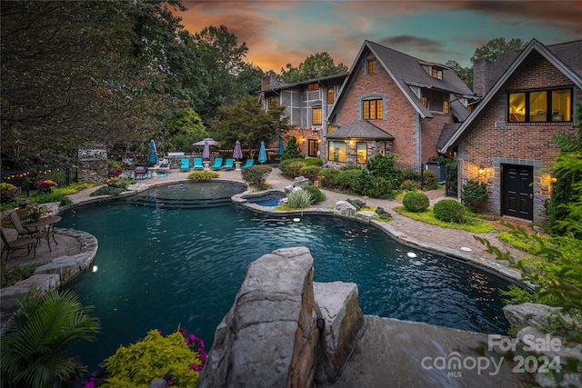 pool at dusk with a patio and central air condition unit